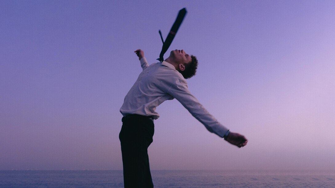 A young man celebrating freedom at sunset by the sea, reflecting the power of rewriting one’s story
