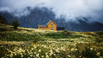 Solitaria casa en medio de una pradera frente a un paisaje montañoso