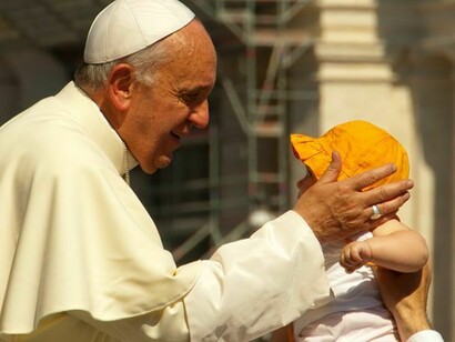 El Papa Francisco coge entre sus manos a un niño