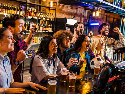 Football supporters celebrating together over drinks while watching a live match in a pub