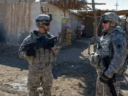 A military patrol moving along a dusty street in Diyala, Iraq, during active conflict