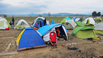 Tents in Idomeni, Greece, with a plea for help to open the borders, reflecting the desperation and hopes of refugees amid a humanitarian crisis