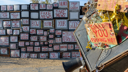A wall of truth, TVs with words of fake news and propaganda messages in front of an old news camera
