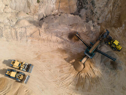 Heavy machinery operates in an open-pit quarry, carrying out industrial activities in a surface mine
