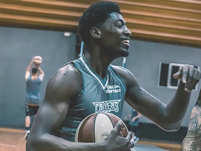 A youthful man holds a basketball in his hand, exuding a sense of athleticism and readiness for the game