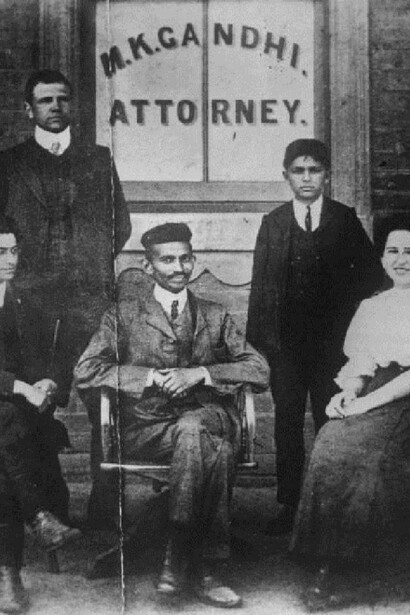 Mahatma Gandhi (Mohandas Karamchand Gandhi, 1869 - 1948) when he was practising as an attorney in South Africa. He is seated in front of a window bearing his name, on the left is H S L Polak then his clerk. The woman is Miss Schlesin, a Russian. (Photo by Keystone/Getty Images)