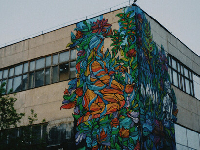 A weathered city building covered in graffiti under a cloudy sky