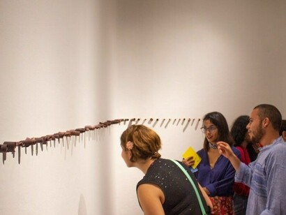 Asistentes contemplando la obra de Alessandro Valerio, «Maíz pujagua», montaje en pared, 2019