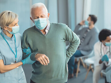 Caring nurse assisting senior man who came do medical appointment at the clinic