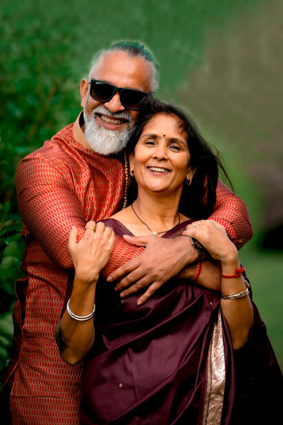 Wearing vibrant traditional attire, an elderly Indian couple stands side by side, radiating happiness and lifelong companionship