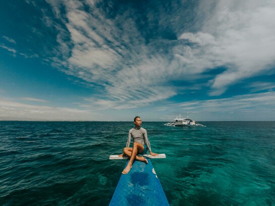 A woman wearing a rash guard in the sea in the Philippines, enjoying a peaceful travel moment