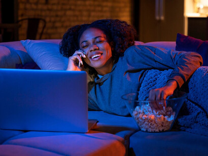 As streaming platforms diversify, a woman watches her favourite niche content on a laptop, embracing the wide array of options available in today’s entertainment landscape