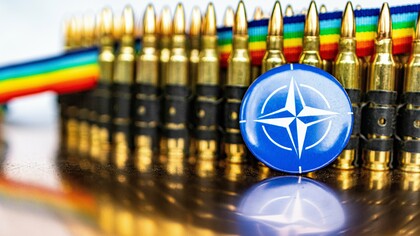 A NATO pin badge in front of bullets, representing the military alliance between member countries to promote peace and security 