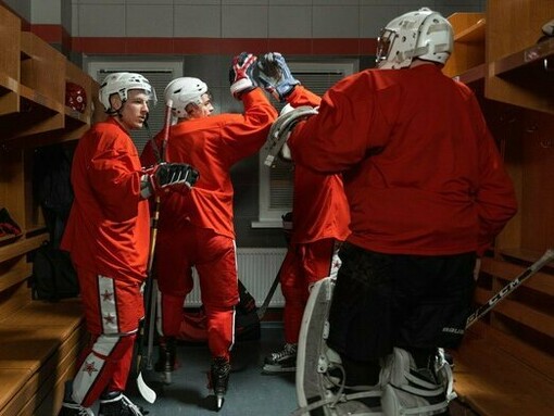 Hockey players exchanging a celebratory high-five in the locker room, representing teamwork built around a shared objective