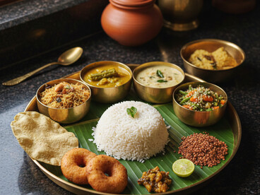 A wholesome and traditional Brahmin meal is presented on a brass thali, featuring soft rotis, fragrant white rice, a vibrant spinach curry, a potato and pea curry, and cooling raita. The combination highlights the pure and balanced flavors of South Indian vegetarian cuisine