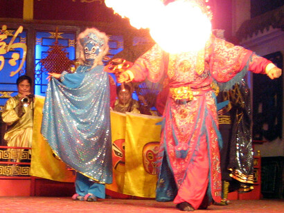 Ópera de Sichuan. Casa de té Shu Feng Ya Yun, Chengdu.
Otra especialidad de la Ópera de Sichuan es la actuación de escupir fuego que se ve aquí. El artista de la izquierda lleva una máscara de cambio rápido, las máscaras en los rostros de los personajes se cambian tan rápidamente que el ojo (y mucho menos la cámara fija) no puede captar su movimiento