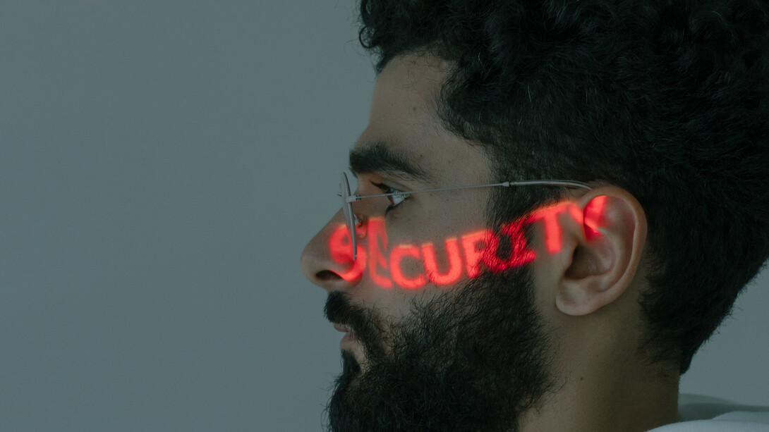 Jovem programador tem a palavra segurança projetada em seu rosto