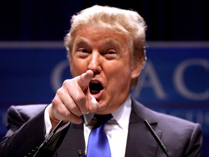 Donald Trump speaking at a press conference, pointng his finger a the camera
