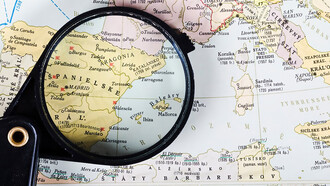 A magnifying glass revealing a map of Spanish cities