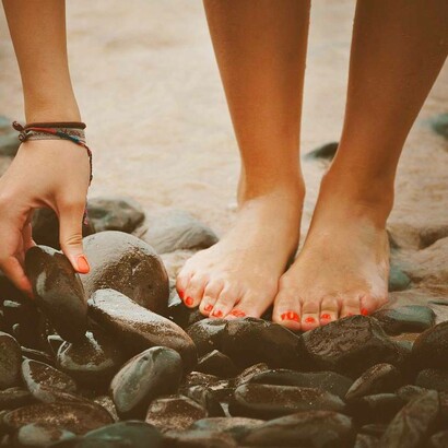 Piedi di donna su ciottoli neri: "Il primo testo che mi sento di chiamare poesia l’ho scritto in Sardegna, sulle rocce in riva al mare. Ero felice. L’ambiente esercitava in me una forza attrattiva, quasi risucchiante"