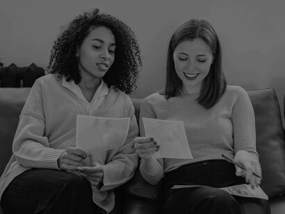 Two women comparing the different angles from the pictures in their hand