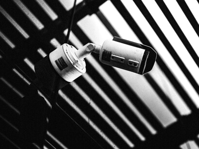 Una cámara de seguridad destaca entre líneas de luz y sombra en una estructura arquitectónica