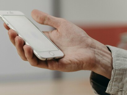 Un homme tenant son smartphone, sur le point de commencer à envoyer des SMS ou à faire défiler les réseaux sociaux