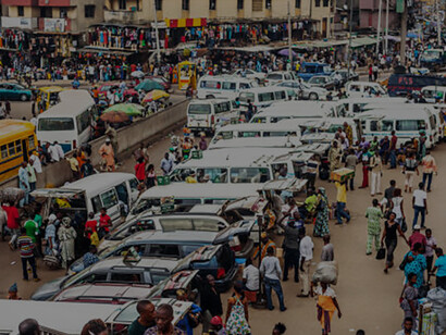 A lively scene in Nigeria, showcasing crowded streets teeming with cars and traffic, highlighting the challenges of urban mobility