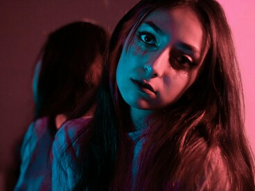 A woman looking at the camera with quiet intensity, symbolising the courage to face herself honestly