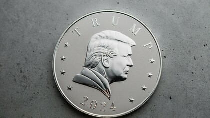 A detailed close-up of a 2024 pure silver coin featuring President Donald J. Trump, placed on a simple textured background