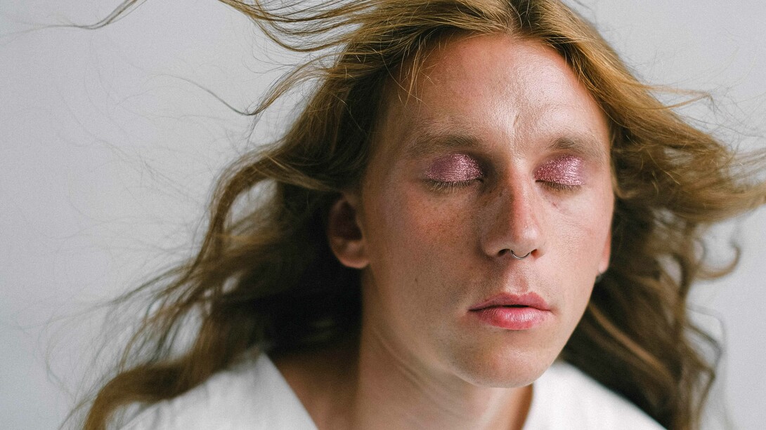 Modelo fecha os olhos para mostrar cores sintilantes em maquiagem nas pálpebras