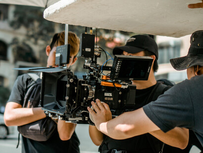 Behind-the-scenes photo of a film crew gathered near the cameras and lights during production