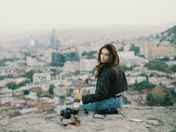 A young woman sitting alone above the city, quietly overlooking the skyline
