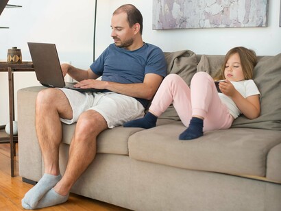 Pai e filha utilizam dispositivos eletrônicos juntos em um ambiente doméstico. A cultura digital modifica a relação com os textos e acelera a circulação das informações, mas não elimina a necessidade de atenção e interação