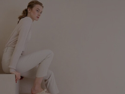 A woman, dressed in minimalist clothing, stands gracefully in a sleek, minimalist environment