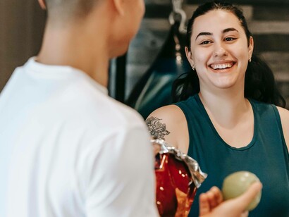 A woman smiling while her trainer holds up an apple