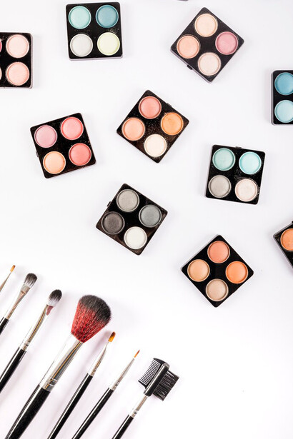 Colorful eye shadow powders and brushes on white backdrop