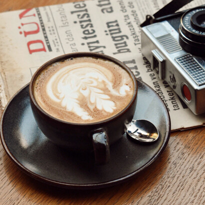 Un periódico, una taza de café y una cámara analógica evocan distintas formas de acercarse a la actualidad: leer, observar y registrar los acontecimientos