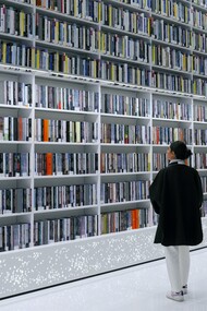 Mulher explora livros em estante de biblioteca