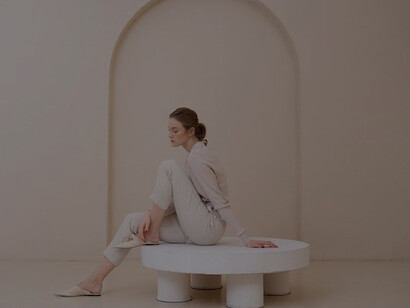 Dressed in refined minimalist fashion, a beautiful woman harmoniously blends with her elegantly sparse surroundings