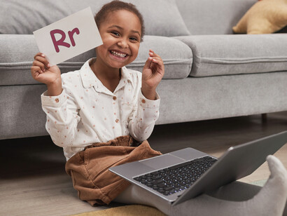 Criança segurando um cartão com letras do alfabeto em forma maiúscula e minúscula