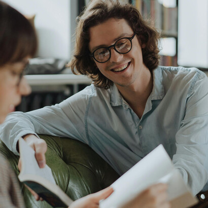 Hombre sonriendo mientras comparte lecturas y tiempo con una mujer. Nuestra esencia está presente en el abrazo simple y profundo con un ser querido