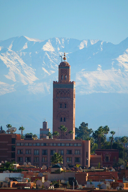 Le minaret s’élève dans la lumière du soir, avec les montagnes de l’Atlas comme arrière-pays éternel de la ville de Marrakech au Maroc