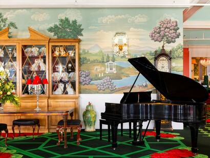 An Afternoon Tea Parlor with a grand piano, vibrant colors and classic décor, reflecting the artistic flair and old-world sophistication of the Grand Hotel
