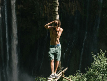A man stands on the edge near a waterfall, capturing the moment—a powerful symbol of breaking free from limits and embracing bold choices