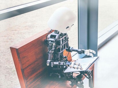A robot on a bench working on a computer