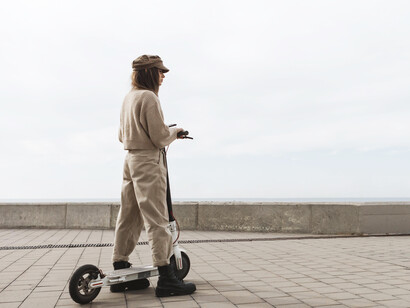 A young woman commuting on an electric scooter through a calm, pedestrian-friendly urban environment