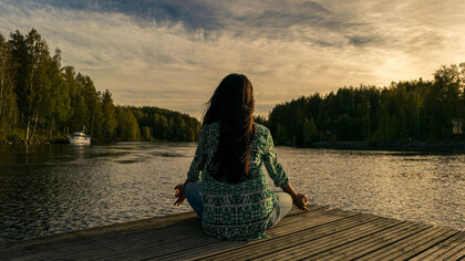 Mujer practicando yoga junto a un lago