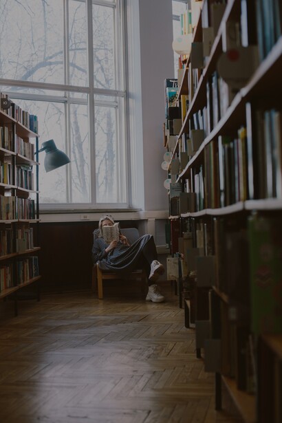 Jovem lê um livro na biblioteca