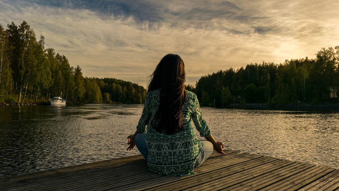 Mujer practicando yoga junto a un lago